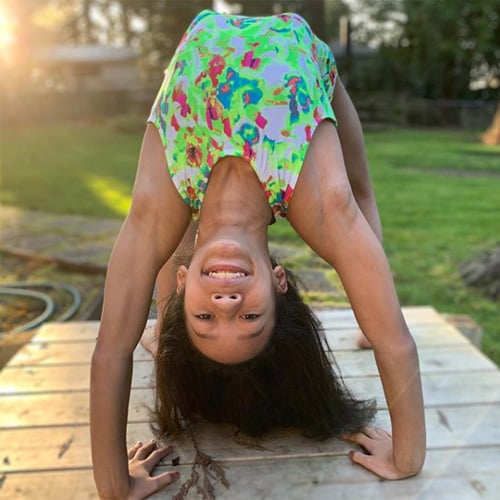 Gymnast doing a backbend in a green Snowflake Designs leotard.