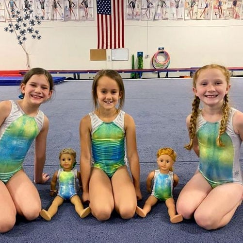 A group of gymnasts and dolls in matching green leotards.
