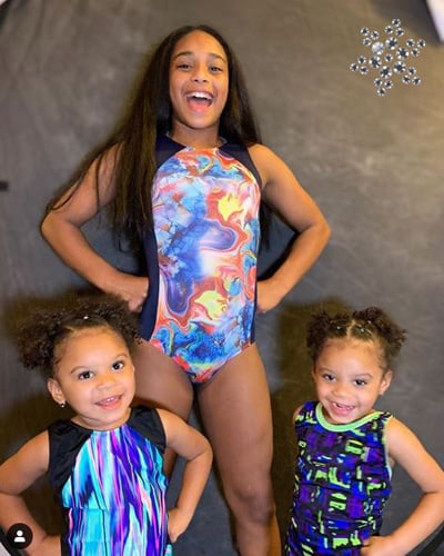 Three gymnasts in bright gymnastic leotards.