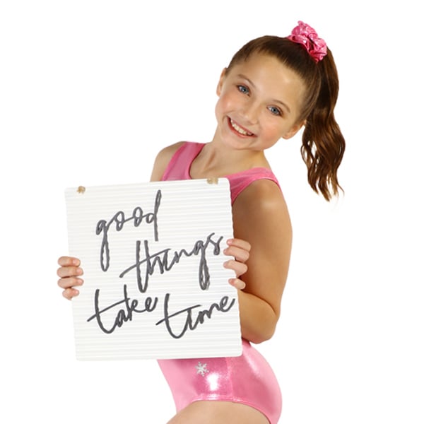 A gymnast in a pink leotard holding a sign