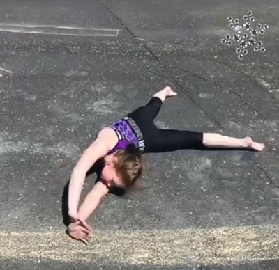 Gymnast doing a skill on a chalk beam in a purple gymnastic leotard.