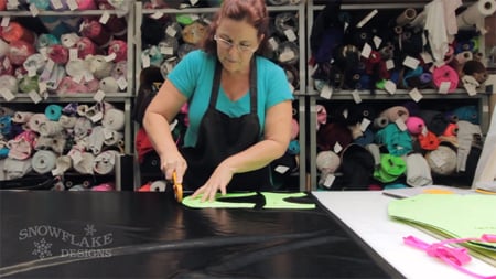 woman cutting out snowflake design new leotard from fabric
